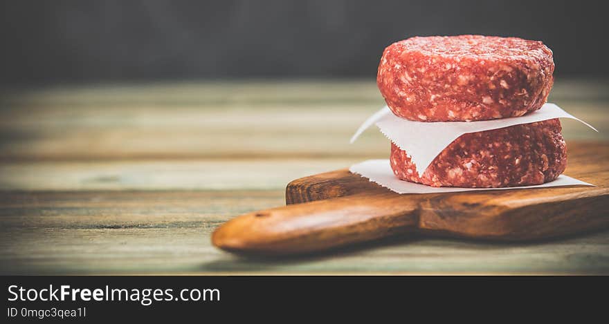 Raw burgers - cutlets from organic beef meat on wooden background, space for text