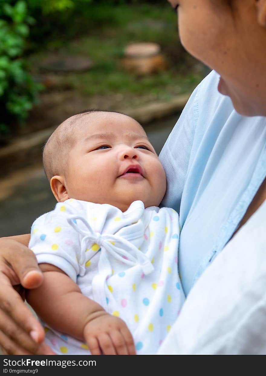 Portrait of happy Asia mother holding his newborn sweet baby dressed. The mommy embracing her baby with love and care. her daughter always happy when she is held.