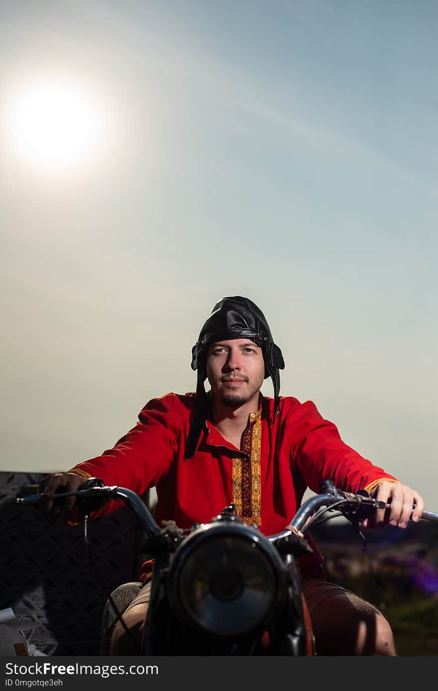 Russian young motorcyclist on an old Soviet motorcycle on sky background