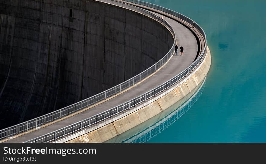 Two people walking on a dam wall Valais, Switzerland