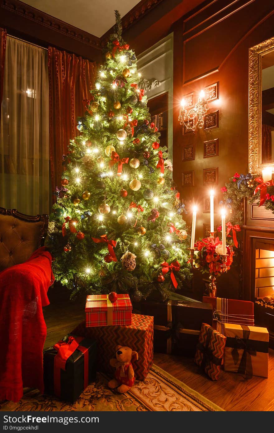 Gifts at the Christmas tree. Christmas evening by candlelight. classic apartments with a fireplace.