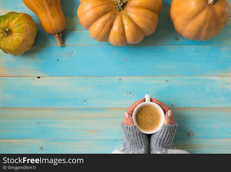 Woman`s hands in sweater holding cup of coffee on the blue wooden table. Holiday concept. Girl holding a coffee cup on a wooden vintage background - winter time concept.Holiday concept. Woman`s hands in sweater holding cup of coffee on the blue wooden table. Holiday concept. Girl holding a coffee cup on a wooden vintage background - winter time concept.Holiday concept.