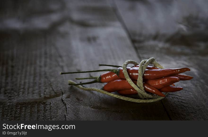 Red hot chili peppers tied by a string on a rustic wooden table. Copy space