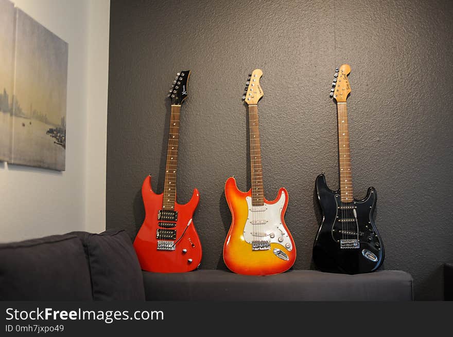 The Three electric guitars of different colors on the couch