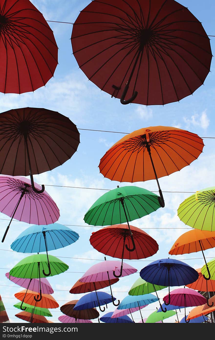 Street installation with colorful, beautiful umbrellas floating in the air against the sky.