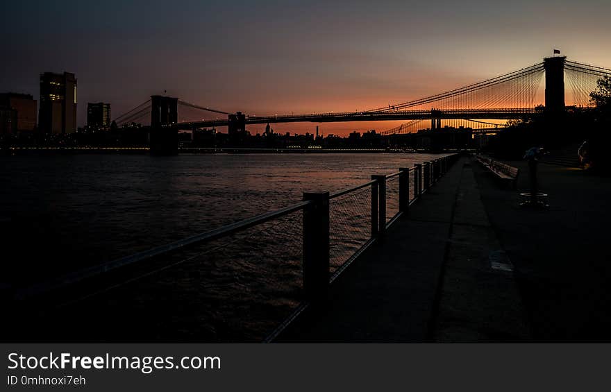 Silhouette Of The Brooklyn Bridge At Sunrise With Reflection In