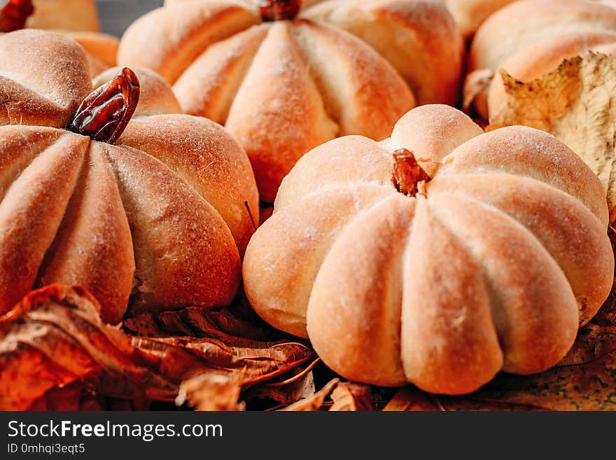 Homemade cakes in the shape of pumpkin with autumn leaves close up. Halloween sweets concept