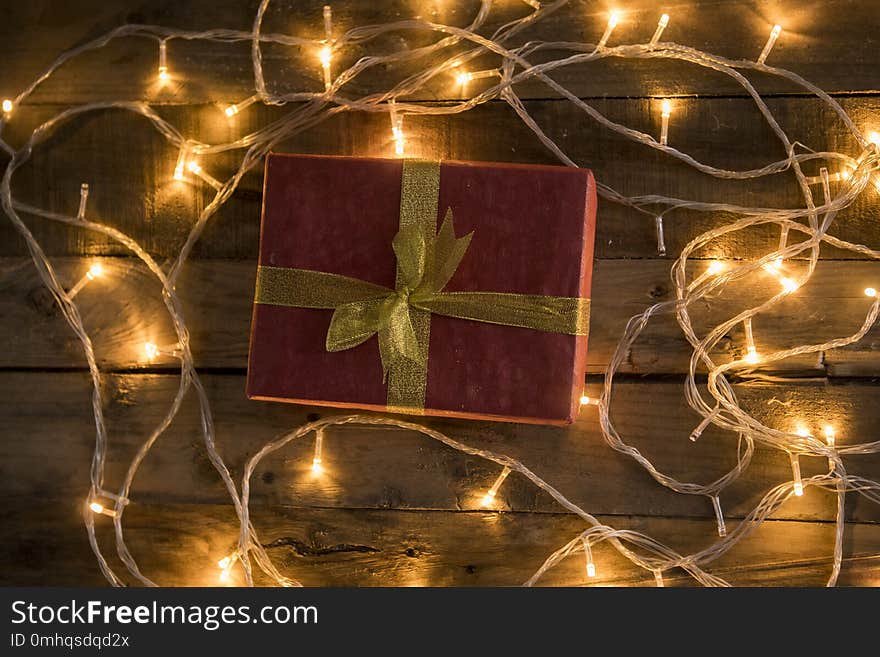 Christmas gift shot with glowing christmas lights on vintage wooden background. Christmas gift shot with glowing christmas lights on vintage wooden background