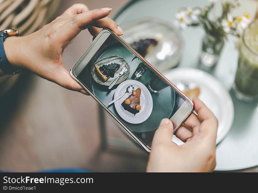 Woman`s hand was photographed cake by her smartphone to get into