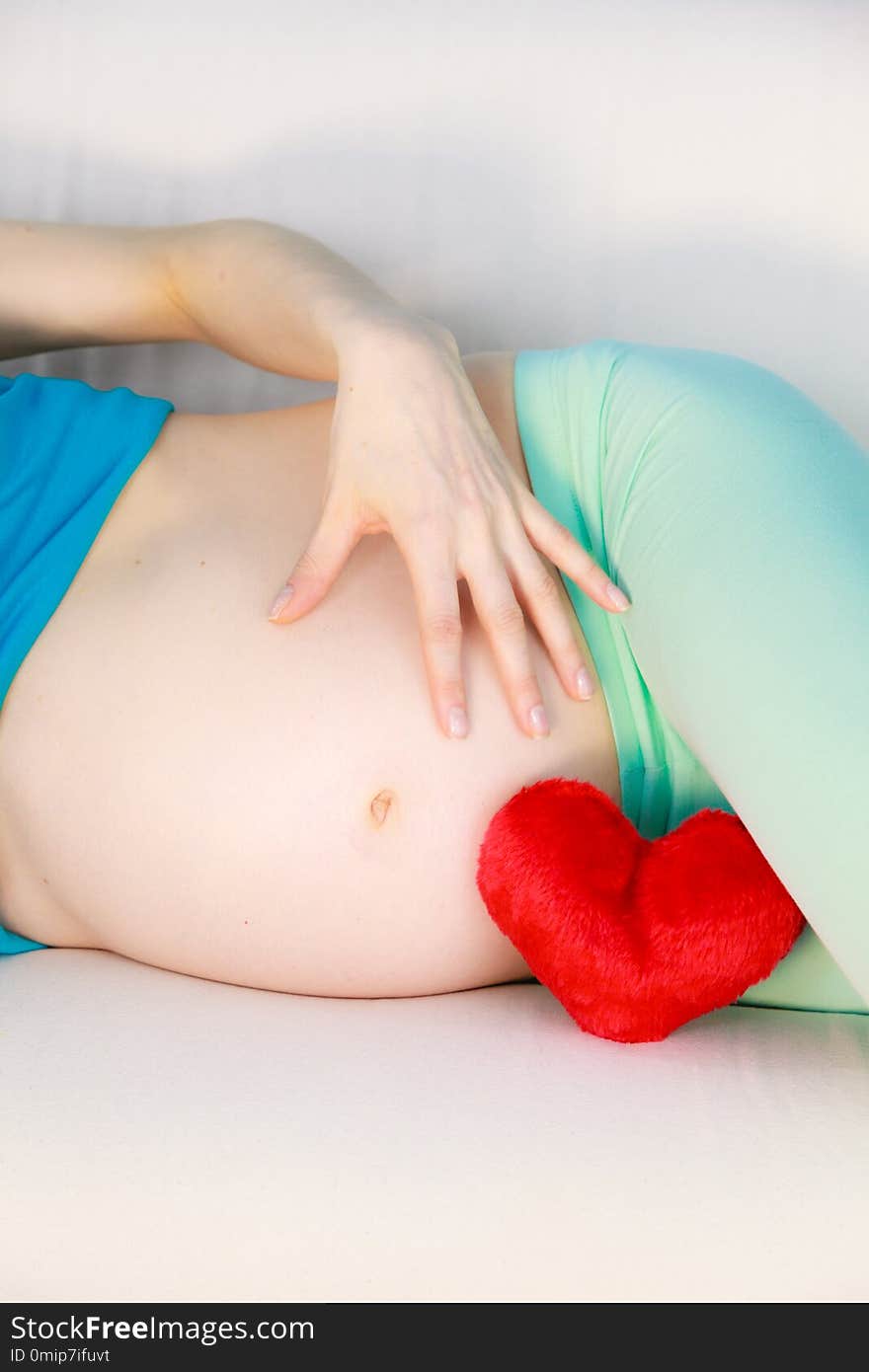 Pregnant woman lying on couch touching her belly