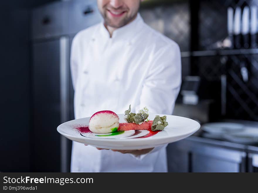 Smiling happy cook holding a prepared dish