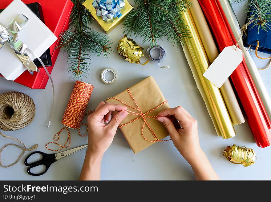 Woman`s hands decorate present box on gray wooden background. New Year and Christmas decorations concept.