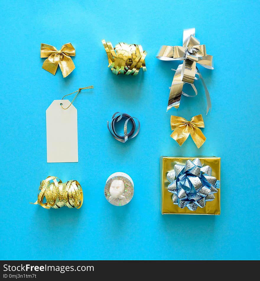 Golden and silver Christmas gift boxes and decorations on blue background. Flat lay. Top view