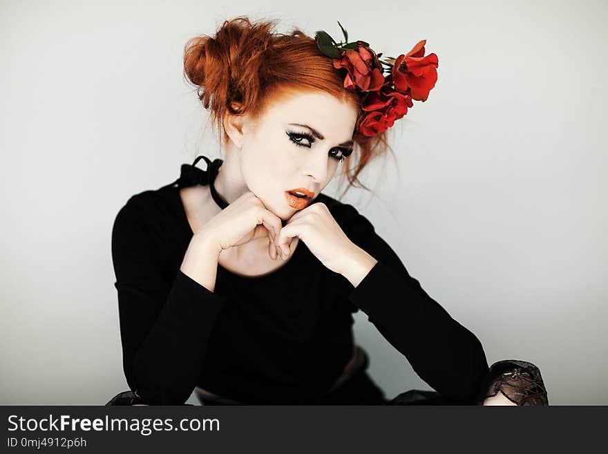 Beautiful, cute woman with halloween make up and red hair poses in front of white background