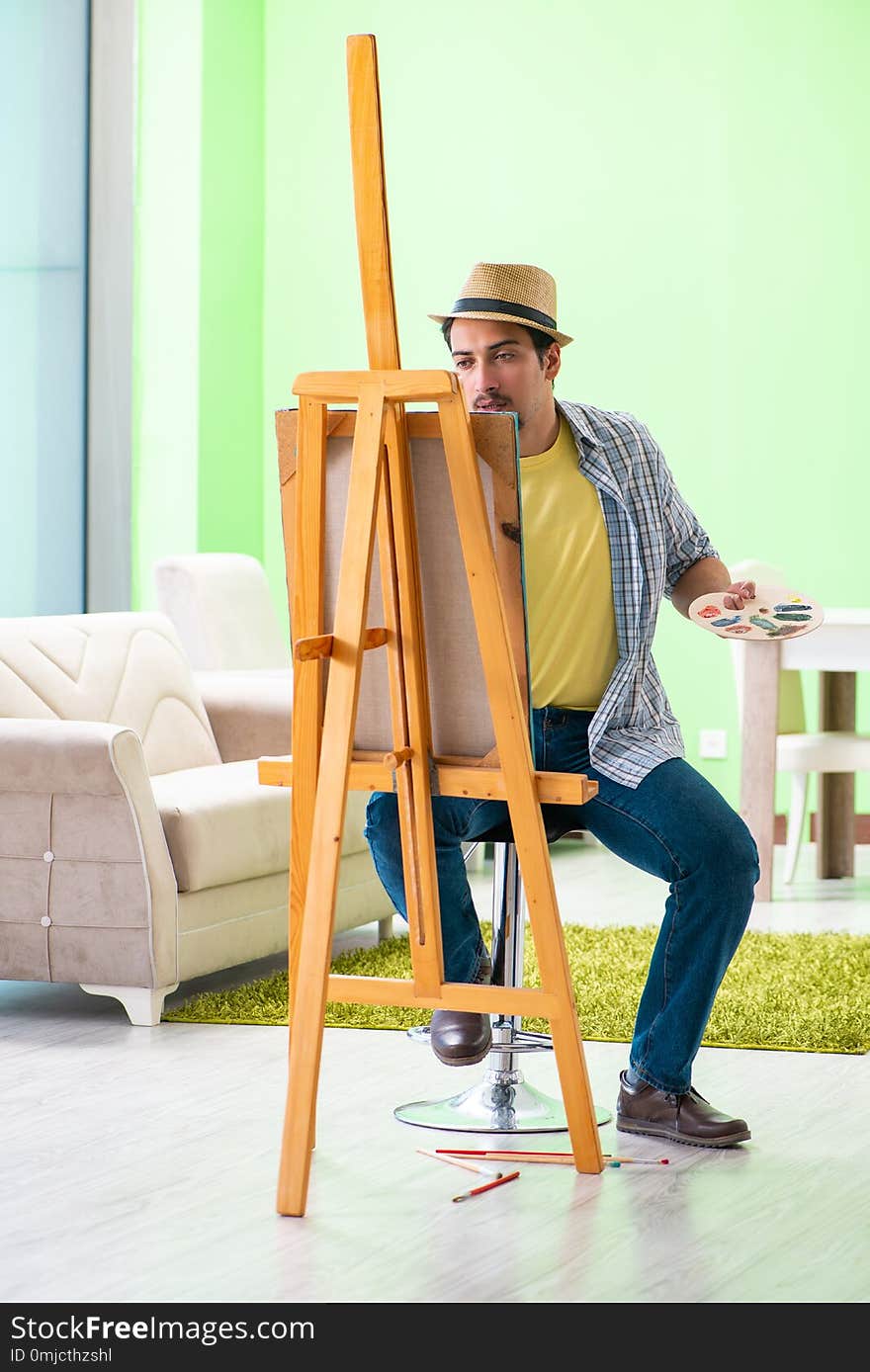 The young male artist working on new painting in his studio