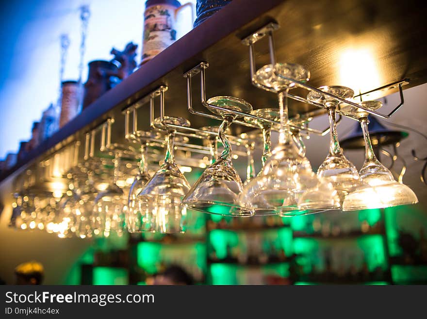 Beautiful cocktail glasses in the bar hang over the table. Nightclub. Alcoholic beverages, many wine glasses have different shapes. Bar counter