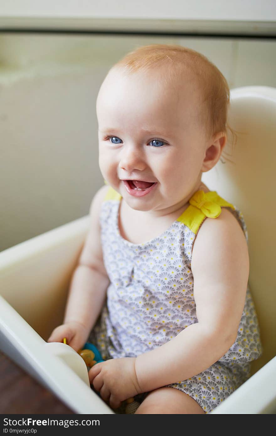 Little baby girl sitting in high chair