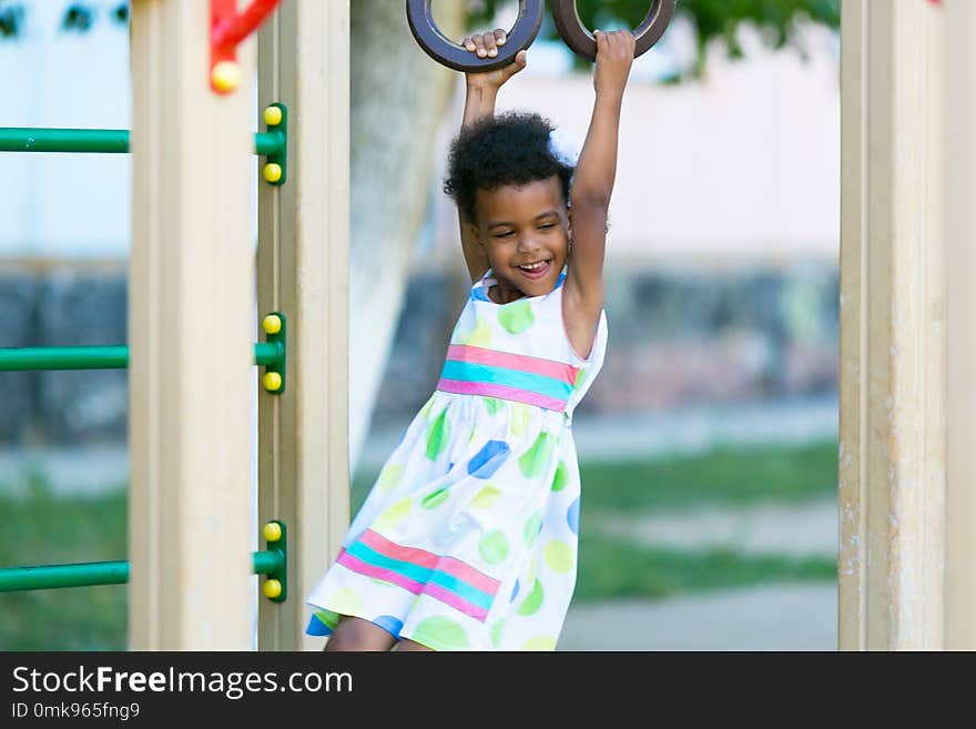 The girl is hanging on the sports rings.