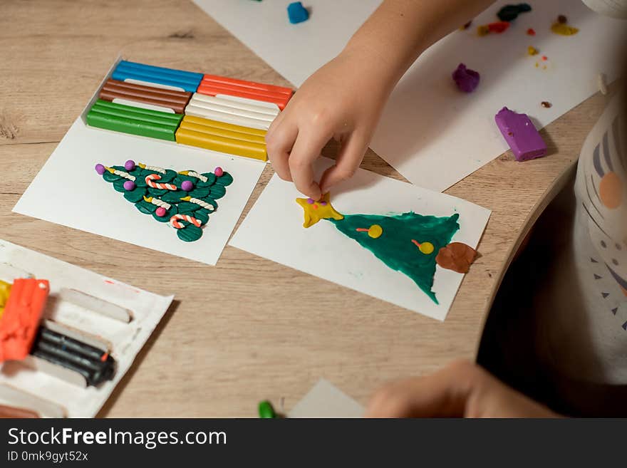 the boy makes a Christmas craft tree decorated with balls and candles made of plasticine. New Years is soon. the boy makes a Christmas craft tree decorated with balls and candles made of plasticine. New Years is soon