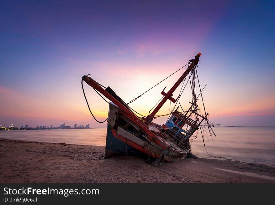 Abandoned shipwreck of wood fishing boat on beach at Twilight ti