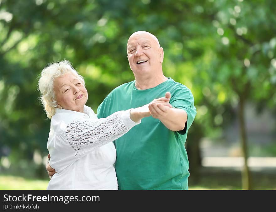 Cute elderly couple dancing outdoors.