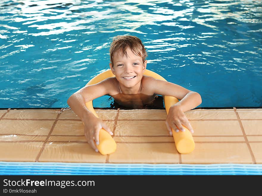 ttle boy with swimming noodle in indoor pool. ttle boy with swimming noodle in indoor pool