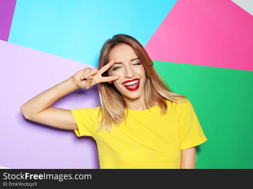 Beautiful young woman with healthy long blonde hair on color background