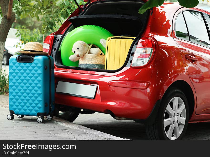 Suitcases and toys in car trunk outdoors