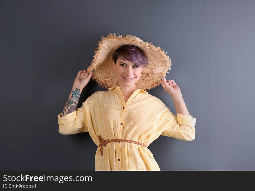 Trendy young woman with tattoo on color background