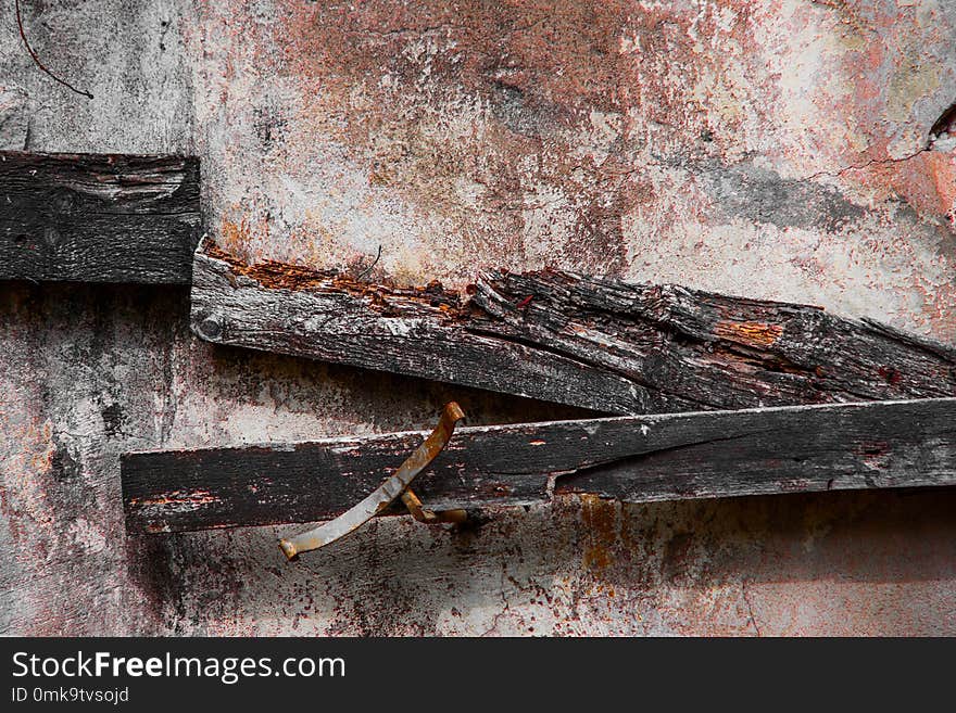 Dirty concrete wall with decaying boards and rusty pieces of metal is close