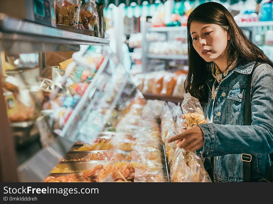 Female customer is talking to the seller in the store what she wants to buy. she is holding a bag of dried fruit. Female customer is talking to the seller in the store what she wants to buy. she is holding a bag of dried fruit.