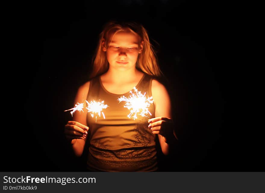 Teenager girl holding a burning sparklers in her hands.