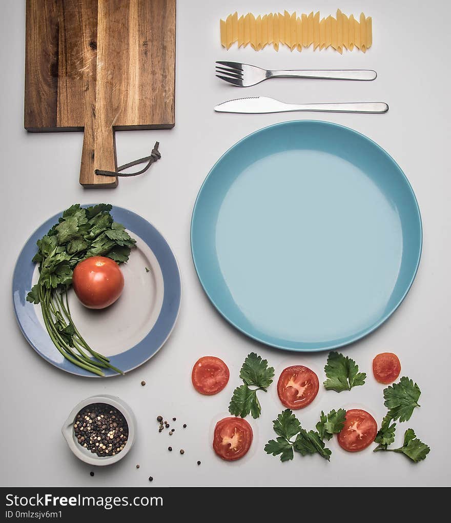 Simple food, tomato, parsley and penne pasta, lined on white background, top view flat lay