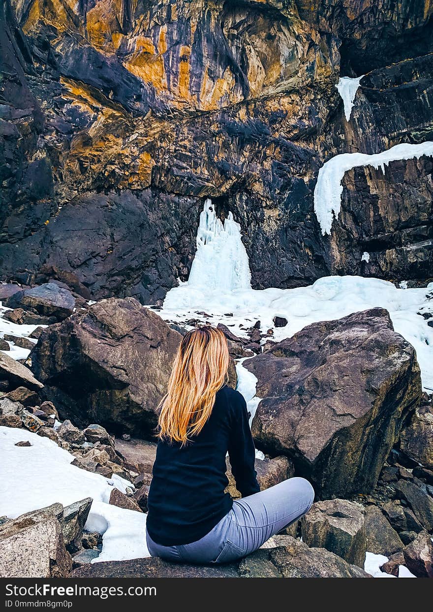 The woman sitting on the rock mountain. The girl relaxing on the top of the mountain, silhouette.