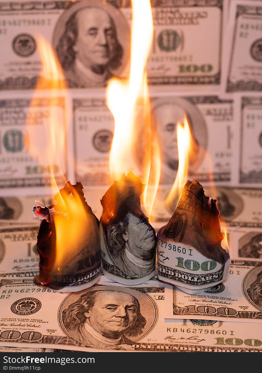 A hunred dollar bill in American US currency is on fire. A hunred dollar bill in American US currency is on fire