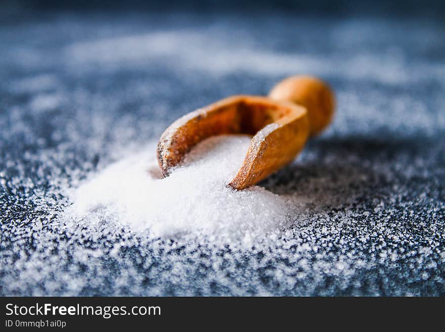 Crystals of shallow salt in a scoop, spoon on a dark gray table.