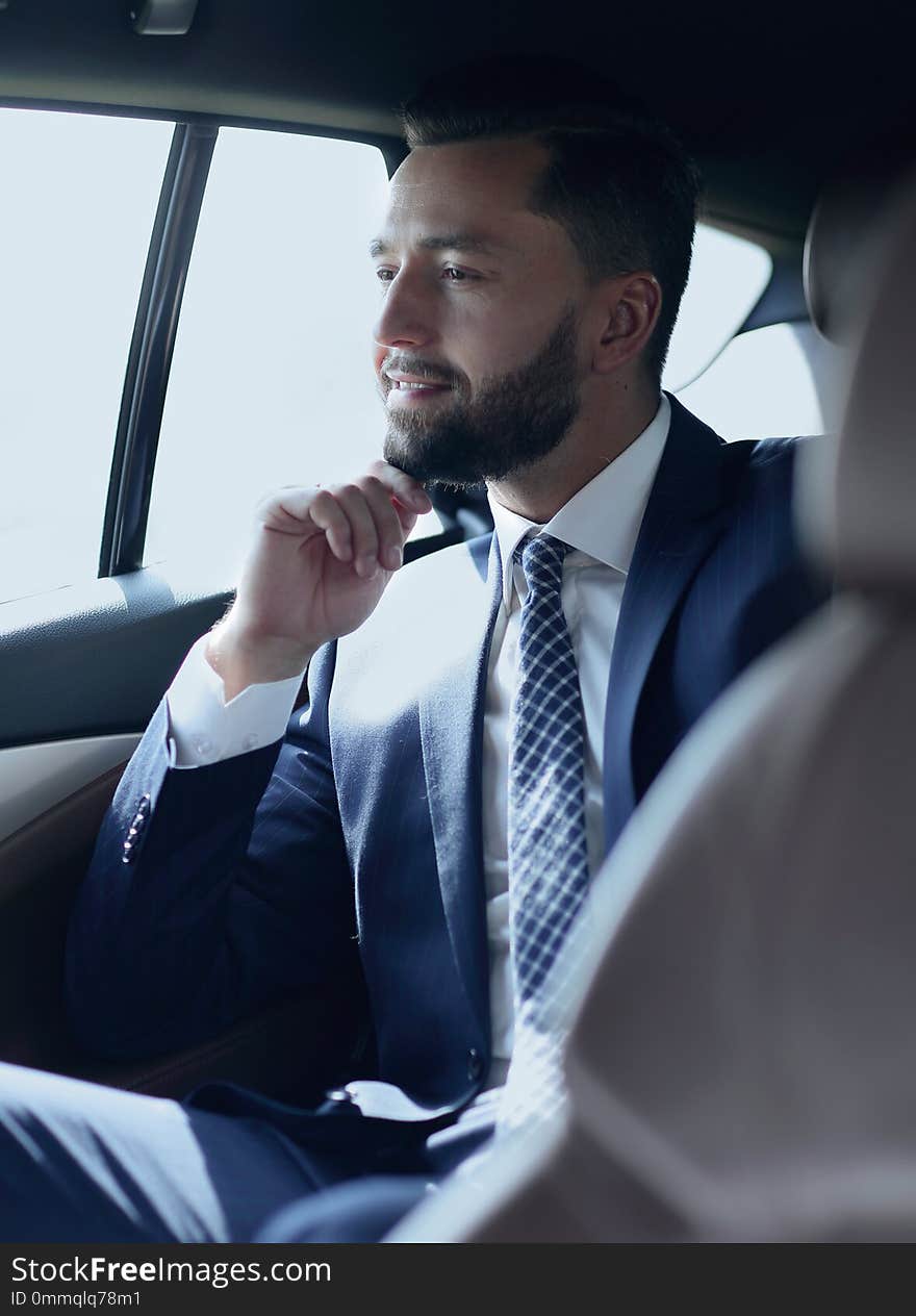 Smiling business man sitting in the back seat of a car