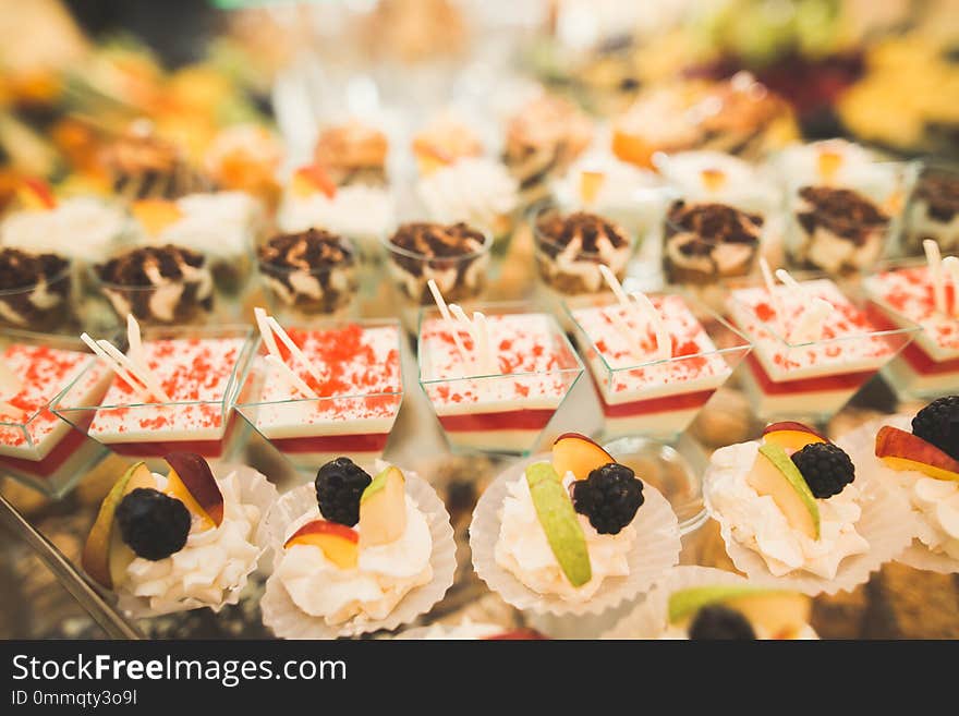 Delicious and tasty dessert table with cupcakes shots at reception closeup