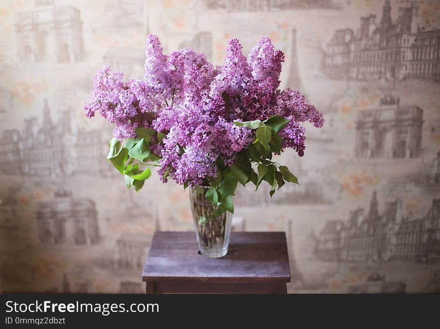 Beautiful large bouquet of lilacs in a glass vase on a wooden stand. Beautiful large bouquet of lilacs in a glass vase on a wooden stand