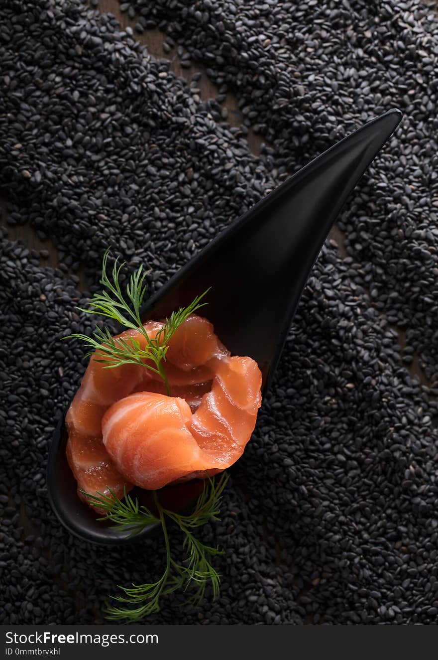 Slice of salted salmon with dill on the background of black sesame. Top view, copy space.