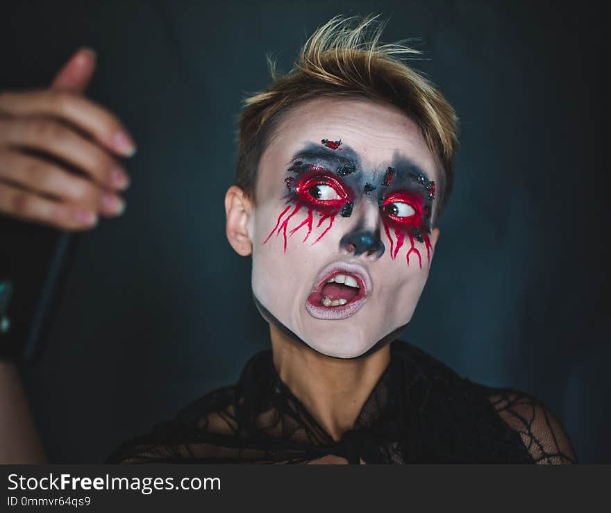 A girl makes selfie in makeup for Halloween.