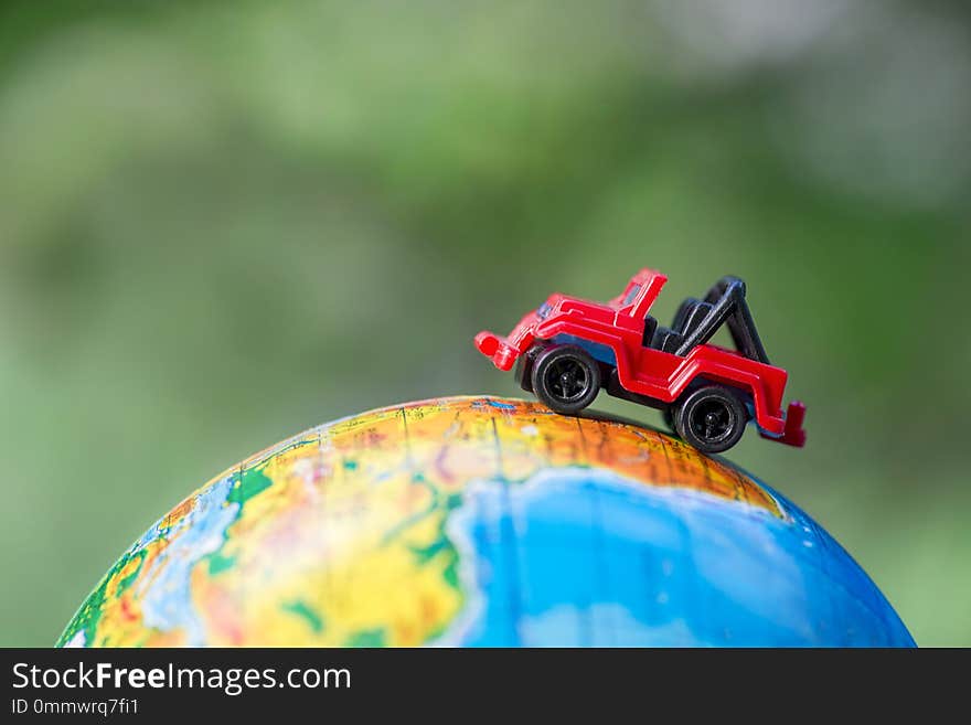 A car on globe on green background. Miniature car toy on globe. Travel concept