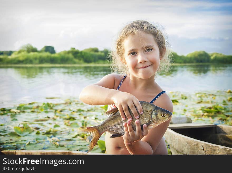 In The Summer Of Bright Sunny Day A Little Girl On The River Caught A Large Bream.