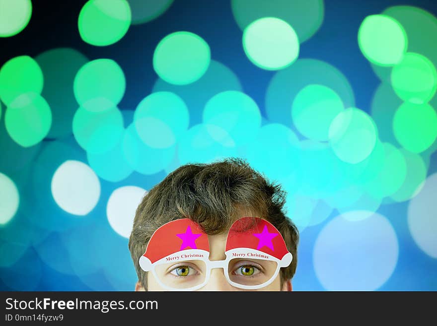 Portrait of cheerful, attractive man on blue background with copy space for text, look over christmas glasses. Portrait of cheerful, attractive man on blue background with copy space for text, look over christmas glasses.