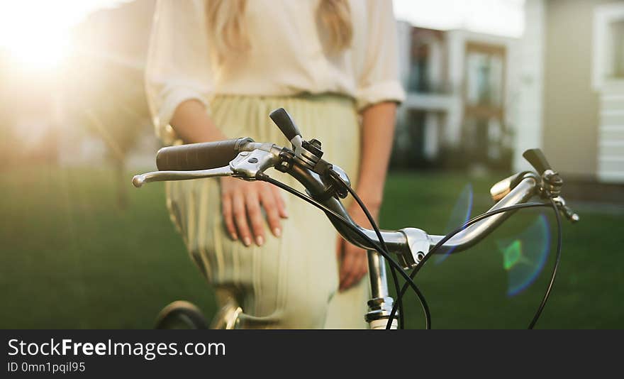 Young stylish woman with a bicycle. Hipster Girl with Bike on Urban Background. Close up hands of a young girl on vintage bicycle in park.