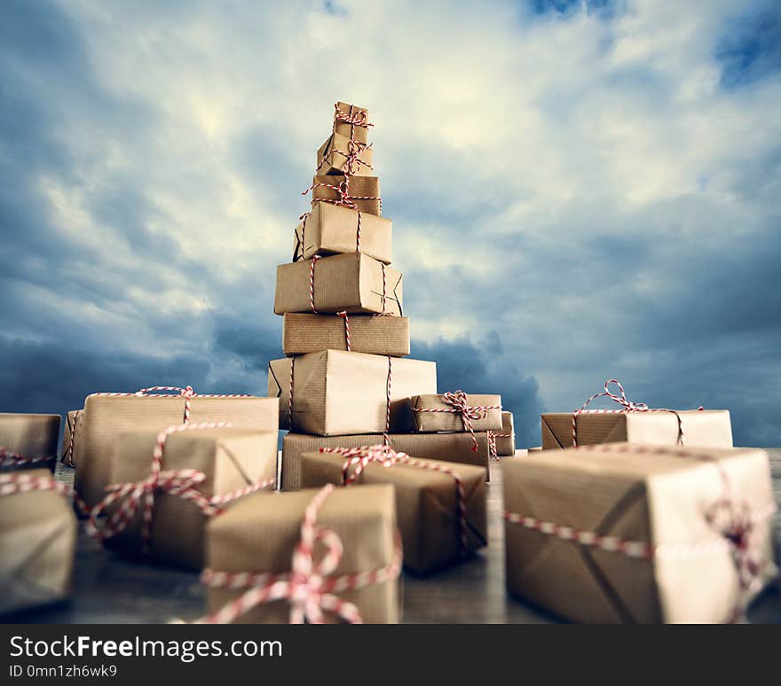 Pile of Christmas gifts wrapped in brown paper against the clou