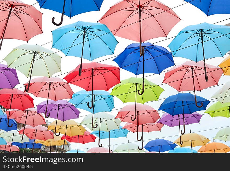 Many opened multicolored umbrellas on light background