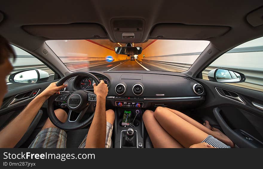 Driver`s hands on a steering wheel of a car and woman in the passenger seat. Road trip on the Italians road before tunnel.