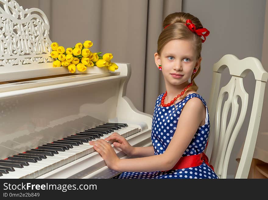 Girl schoolgirl near the piano on which lies a bouquet of flower