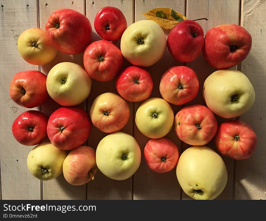 Autumn gifts, set of apples, red and green, juicy, appetizing, shiny peel, on a white wooden table